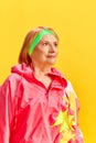 Portrait of beautiful middle-aged sportive woman in colorful comfortable sportswear posing against yellow studio