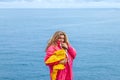 portrait of beautiful middle aged woman wearing a pink windbreaker in front of a blue sea Royalty Free Stock Photo