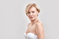 Portrait of beautiful middle aged woman in white bra looking serious at camera, posing isolated against grey background Royalty Free Stock Photo