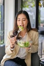 Beautiful Asian businesswoman having brunch, enjoying eating healthy salad bowl at the cafe Royalty Free Stock Photo