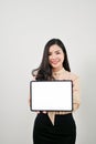 Beautiful Asian female office worker showing a digital tablet empty screen, isolated background Royalty Free Stock Photo
