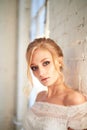 Portrait of a beautiful miniature bride in a lace dress. Hair with curls. Emphasis in make-up on the eyes.Blonde.