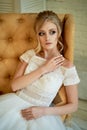 Portrait of a beautiful miniature bride in a lace dress. Hair with curls. Emphasis in make-up on the eyes.Blonde.