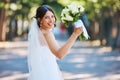 Portrait of a beautiful mixed race bride looking back over her shoulder and holding up her bouquet. Stunning bride