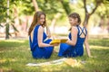 Portrait of a beautiful, modern and young girls in modern dresses in a park. Fashionable and charming young girls with books. Royalty Free Stock Photo