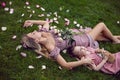 portrait of a beautiful mother and her baby daughter, holding a pet rabbit, lying on a green meadow in summer in pink Royalty Free Stock Photo