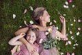 portrait of a beautiful mother and her baby daughter lying on a green meadow in summer in pink dresses. Royalty Free Stock Photo