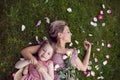 portrait of a beautiful mother and her baby daughter lying on a green meadow in summer in pink dresses. Royalty Free Stock Photo