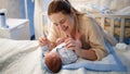 Portrait of beautiful mother holding hands of her little baby son lying on bed at night Royalty Free Stock Photo