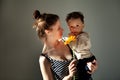 Portrait Beautiful Mother holds baby son and gerbera flower in hand while child looking at camera. Authentic portrait of