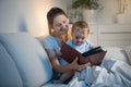 Portrait of beautiful mother reading book to her baby before going to sleep Royalty Free Stock Photo