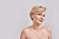 Portrait of beautiful naked middle aged woman looking at camera while posing against grey background. Beauty