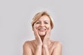 Portrait of beautiful naked middle aged woman looking excited at camera, touching her cheeks while posing Royalty Free Stock Photo