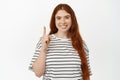 Portrait of beautiful natural redhead girl, ginger women pointing finger up and smiling happy, showing direction, sale