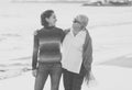 Portrait of beautiful older mom and mature daughter walking on the beach at autumn sunset