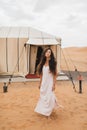 Portrait of young brunette woman in white dress. Glamping tent moroccan desert Royalty Free Stock Photo