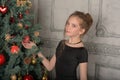 Portrait of a beautiful pensive girl in black near the Christmas tree at Christmas