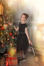 Portrait of a beautiful pensive girl in black near the Christmas tree at Christmas