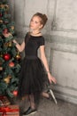 Portrait of a beautiful pensive girl in black near the Christmas tree at Christmas