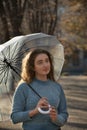 Portrait of beautiful pensive girl with blue eyes and curly hair under transparent umbrella. Young woman in blue sweater Royalty Free Stock Photo