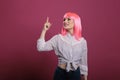 Portrait of beautiful person with pink hair using index finger to point up