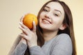 Portrait of a beautiful positive girl with long hair and orange, a young woman smiling and holding fruit near face, healthy eating Royalty Free Stock Photo