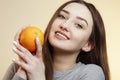 Portrait of a beautiful positive girl with long hair and orange, a young woman smiling and holding fruit near face, healthy eating Royalty Free Stock Photo