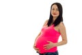 Portrait of beautiful pregnant brunette in pink shirt touching her belly and looking at the camera isolated on white Royalty Free Stock Photo