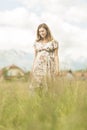 Beautiful pregnant woman in white summer dress in meadow full of yellow blooming flowers. Royalty Free Stock Photo