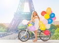 Beautiful girl cycling through Paris with balloons