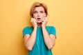 Portrait of beautiful puzzled blonde girl isolated on yellow studio