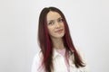 Portrait of a beautiful rebellious young woman smiling, with bright pink hair, standing against a white background.