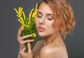 Portrait of a beautiful red-haired curly woman with fresh nude make-up, thick eyebrows and with clean skin,she holds yellow