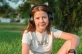 Portrait of a beautiful red-haired teenage girl in headphones in nature. 12 year old girl listens to music Royalty Free Stock Photo