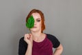 Portrait of a beautiful red-haired woman, half of her face closed by a large green leaf of a Chinese rose. Women`s health, natura Royalty Free Stock Photo