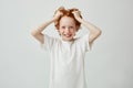 Portrait of beautiful red head child with freckles smiling brightfully with teeth, holding hair in hands and looking in Royalty Free Stock Photo