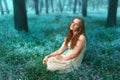 Portrait of beautiful redhead girl sitting on the meadow with forget-me-not flowers Royalty Free Stock Photo