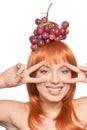Portrait of beautiful redhead young woman with red grapes on head showing peace signs