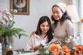 Portrait of a beautiful retired Asian woman focuses on arranging a vase with fresh flowers in a workshop. Lifestyle Royalty Free Stock Photo