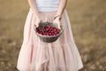 Portrait of a beautiful romantic brunette girl with a basket of cherries in a green garden