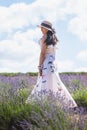Portrait of beautiful romantic woman floral dress and stylish hat in field of lavender flowers Royalty Free Stock Photo