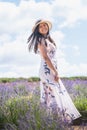 Portrait of beautiful romantic woman floral dress and stylish hat in field of lavender flowers Royalty Free Stock Photo