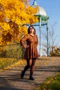 Portrait of beautiful romantic young woman in park with wrought iron gazebo, autumn in Prague, yellow golden leaves, cute stylish