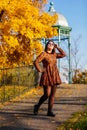 Portrait of beautiful romantic young woman in park with wrought iron gazebo, autumn in Prague, yellow golden leaves, cute stylish