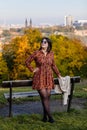 Portrait of beautiful romantic young woman sitting on bench in park, autumn in Prague, yellow brown golden leaves, cute stylish Royalty Free Stock Photo