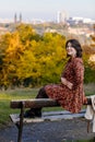 Portrait of beautiful romantic young woman sitting on bench in park, autumn in Prague, yellow brown golden leaves, cute stylish Royalty Free Stock Photo