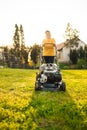 50s senor woman cutting grass with gasoline lawn mower, gardening
