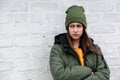 Portrait of a beautiful sad girl in a yellow sweater and khaki hat, which stands near a white brick wall. The concept of emotions Royalty Free Stock Photo