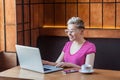 Portrait of beautiful satisfied young girl freelancer with blonde short hair, in pink t-shirt and eyeglasses is sitting in cafe Royalty Free Stock Photo