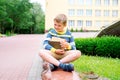 Portrait of Beautiful school boy looking very happy outdoors at the day time. Sitting on the steps with books and a large school Royalty Free Stock Photo